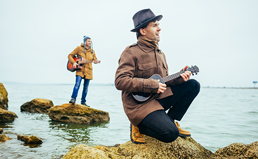 Billede af to mænd der spiller musik på sten i vandet